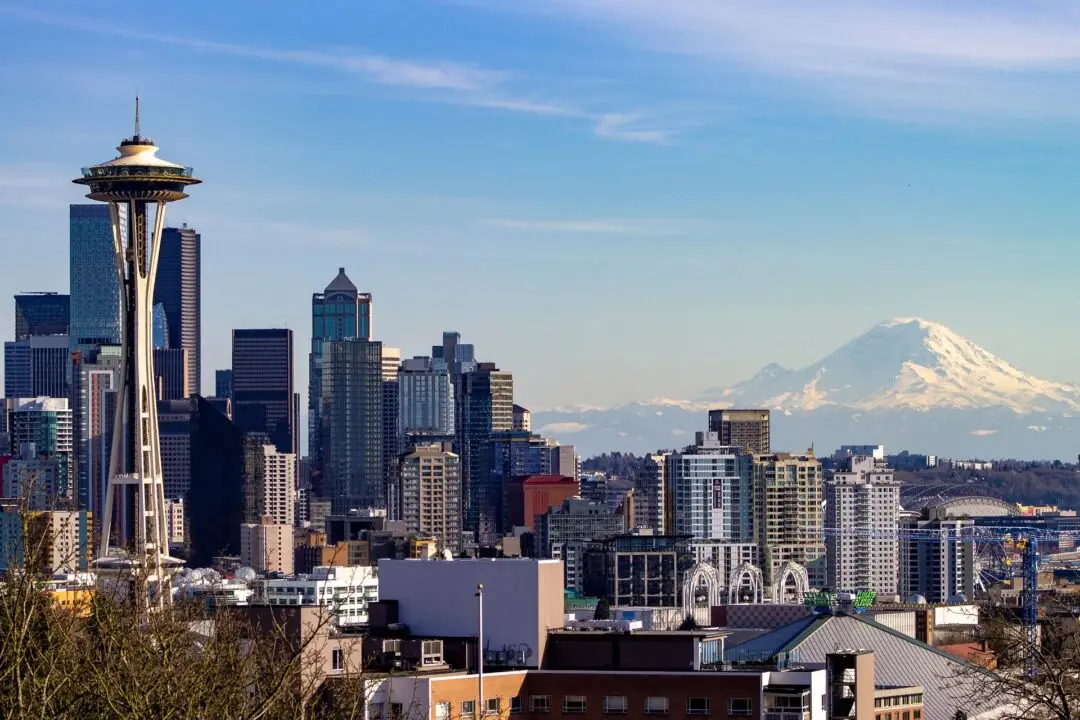 View of Seattle skyline featuring the Space Needle with Mount Rainier in the background under a clear blue sky.