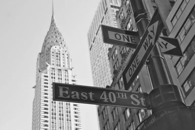 Street signs for East 40th Street and One Way are shown at a New York junction, with the Chrysler Building and surrounding skyscrapers in the background, captured in a striking black and white image.